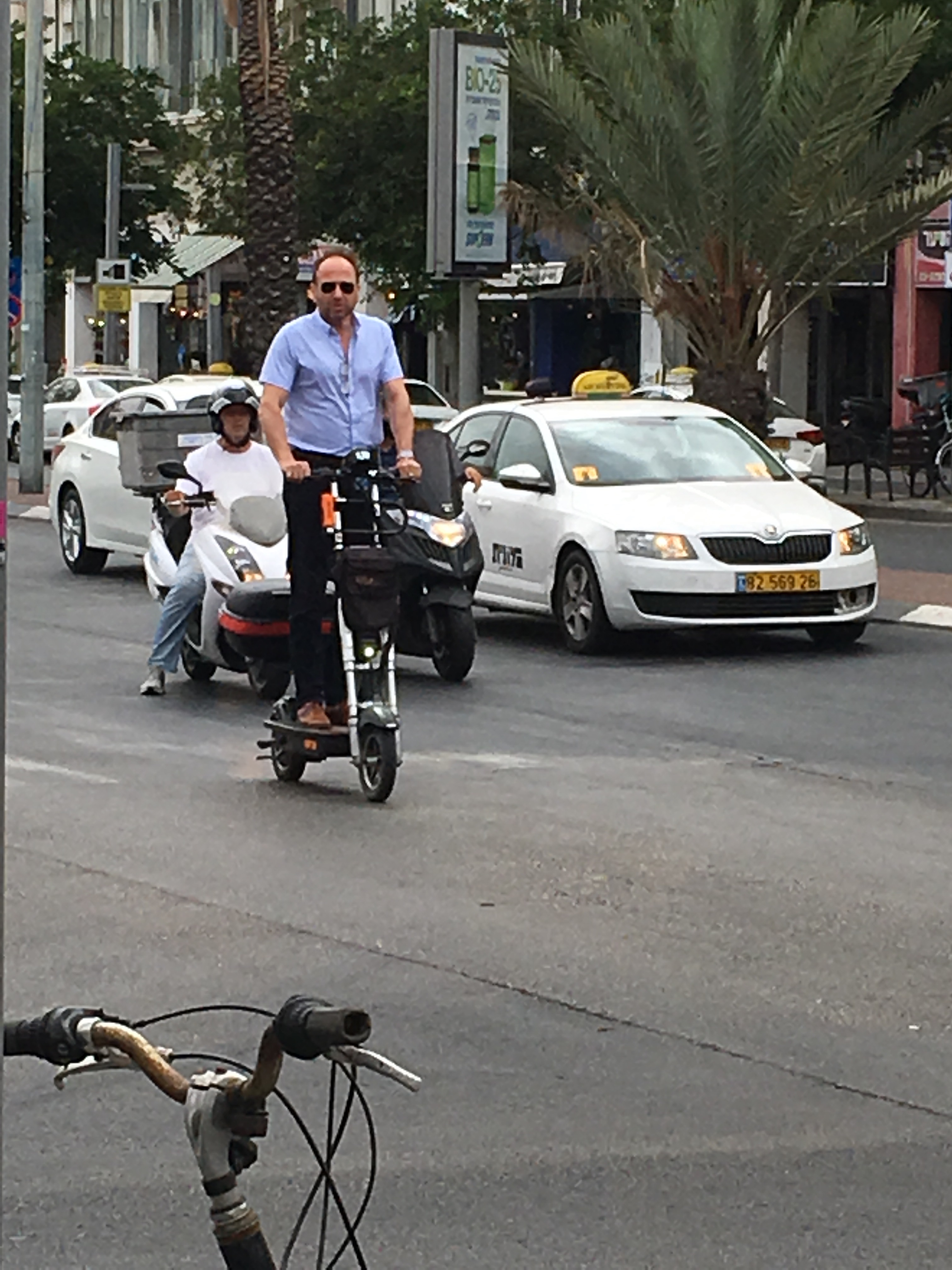 A man on a scooter in traffic. Tel Aviv. Brownell 2019